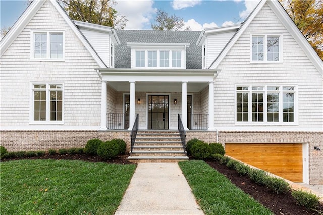 view of front of house featuring a front lawn, a porch, and a garage