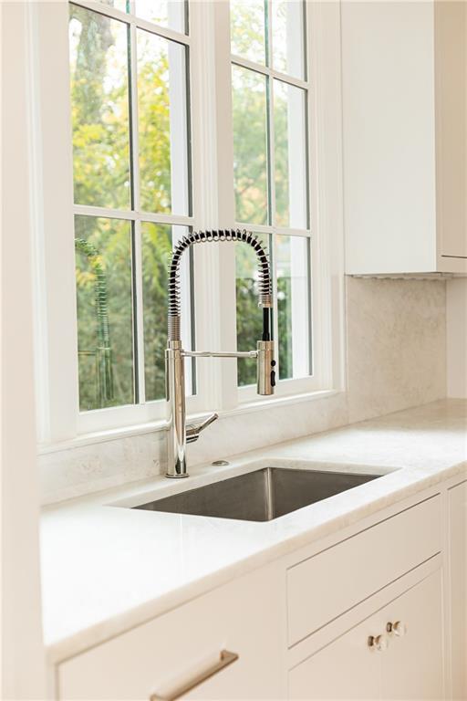 kitchen featuring tasteful backsplash, white cabinetry, and sink