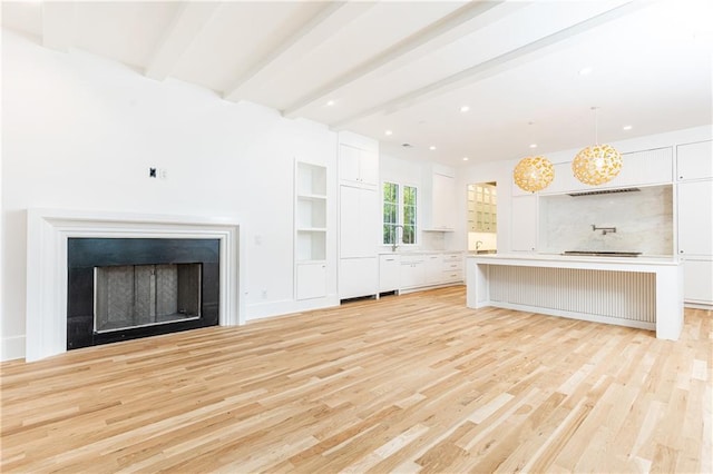 unfurnished living room featuring beam ceiling and light hardwood / wood-style floors