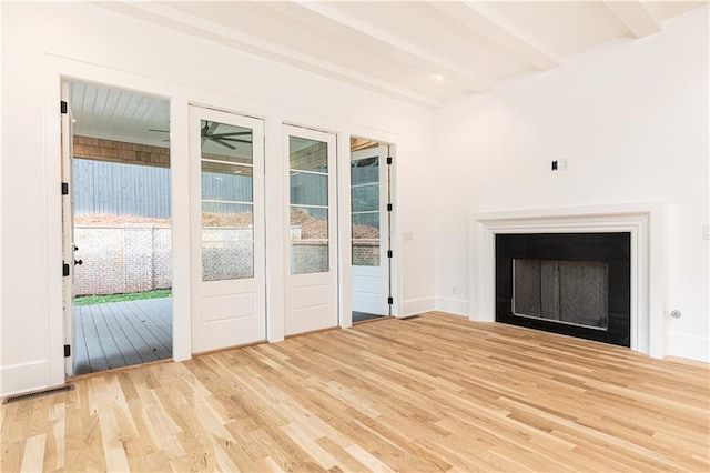 unfurnished living room with beamed ceiling and light hardwood / wood-style flooring