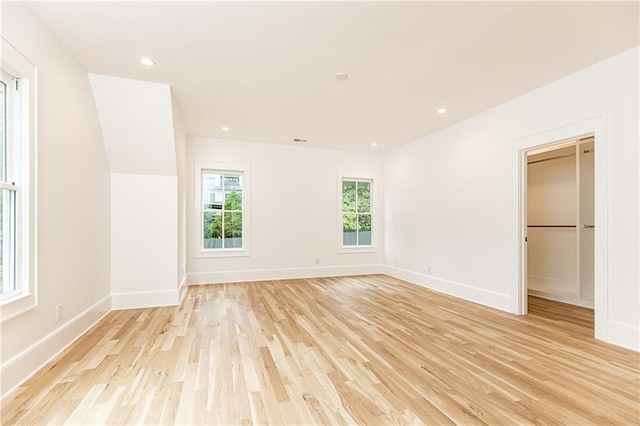 unfurnished bedroom with a walk in closet, light wood-type flooring, and a closet