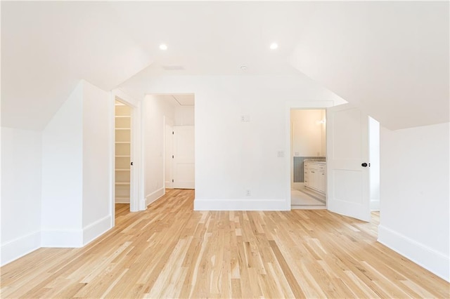 additional living space with light hardwood / wood-style floors and vaulted ceiling