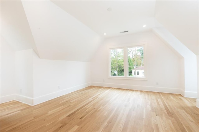 additional living space featuring lofted ceiling and light hardwood / wood-style flooring