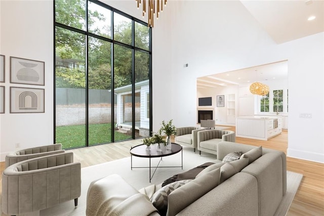 living room with high vaulted ceiling, a chandelier, and light wood-type flooring