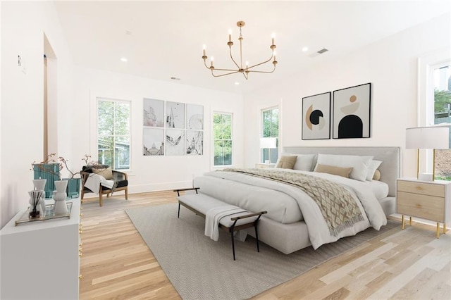 bedroom featuring multiple windows, light hardwood / wood-style floors, and an inviting chandelier