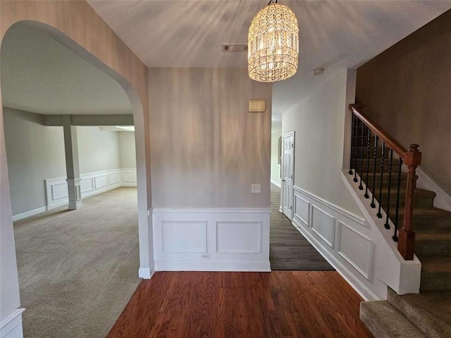 hall with dark wood-type flooring and an inviting chandelier