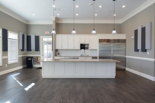 kitchen featuring pendant lighting, white cabinetry, stainless steel built in refrigerator, a large island, and light stone counters