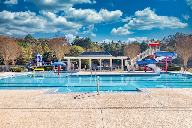 view of pool with a playground, a water slide, and a patio area