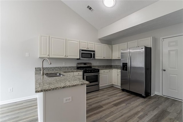 kitchen with sink, kitchen peninsula, high vaulted ceiling, white cabinetry, and stainless steel appliances