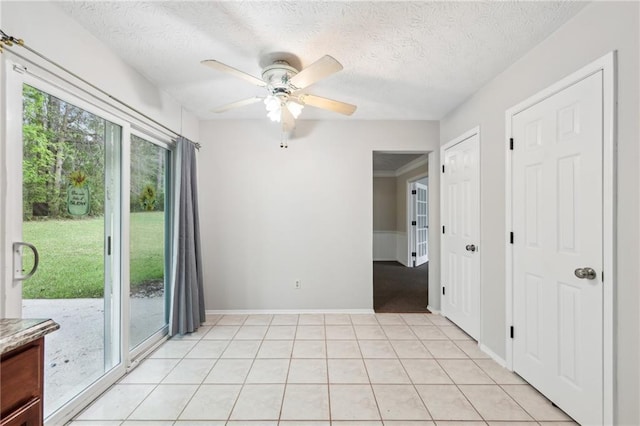 spare room featuring a ceiling fan, baseboards, a textured ceiling, and light tile patterned floors