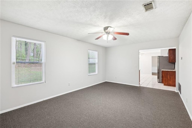 unfurnished room featuring baseboards, a ceiling fan, visible vents, and light carpet
