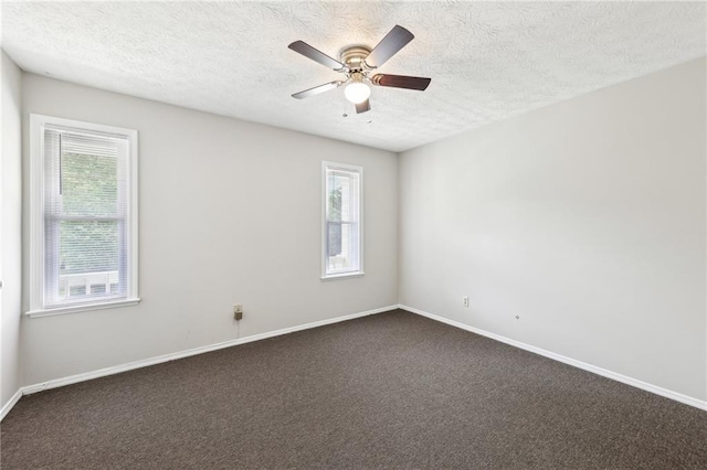 spare room with dark colored carpet, a textured ceiling, a ceiling fan, and baseboards