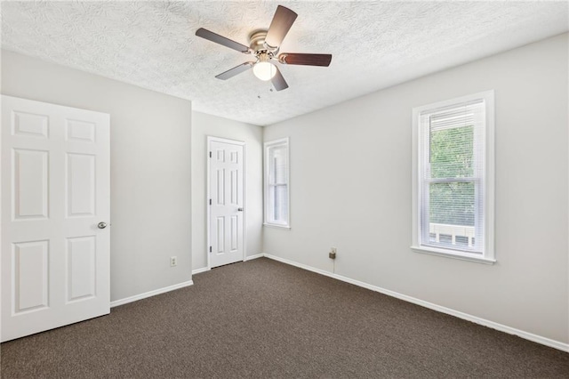 unfurnished bedroom with dark carpet, a textured ceiling, baseboards, and ceiling fan