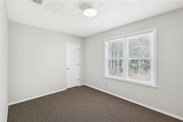 spare room featuring visible vents, dark colored carpet, baseboards, and a textured ceiling