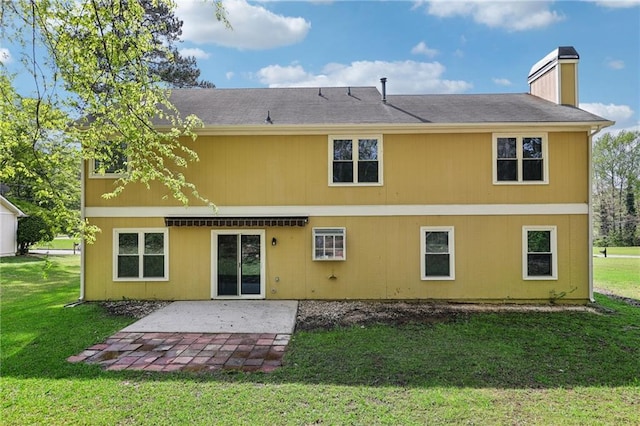 back of house featuring a chimney, a yard, and a patio