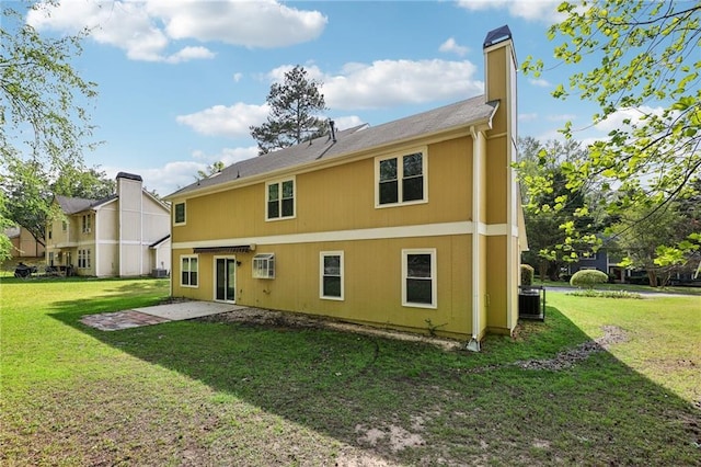 back of property with a yard, a chimney, and a patio area
