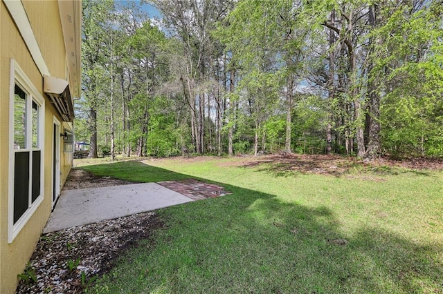 view of yard featuring a patio area and a wooded view