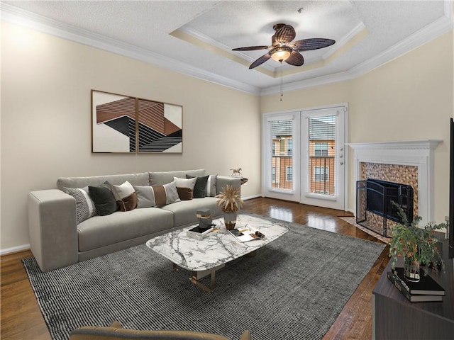 living room featuring a ceiling fan, a raised ceiling, wood finished floors, and ornamental molding