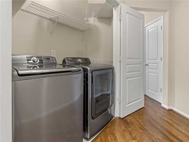 laundry room featuring baseboards, wood finished floors, washing machine and dryer, and laundry area