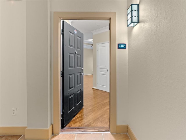 corridor featuring crown molding, baseboards, and wood finished floors