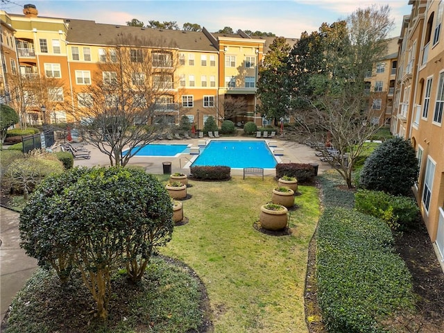 community pool with a yard, a patio area, and fence