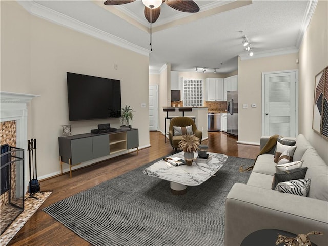 living area with a ceiling fan, dark wood-type flooring, a fireplace, and ornamental molding