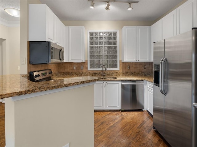 kitchen featuring backsplash, white cabinetry, stainless steel appliances, and a sink