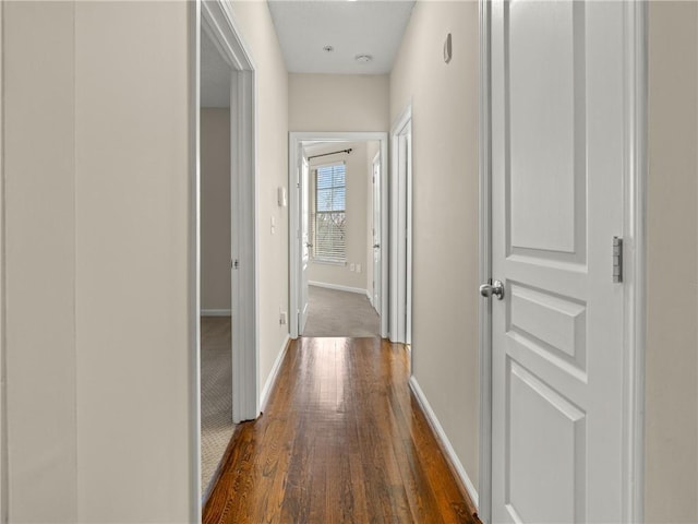 hallway with dark wood finished floors and baseboards