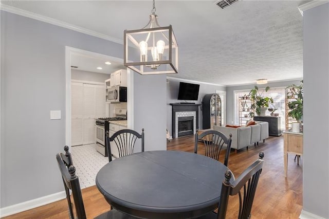 303 Gettysburg Pl, Atlanta, GA 30350 - dining room featuring crown molding, a fireplace, light wood-style floors, baseboards, and a chandelier