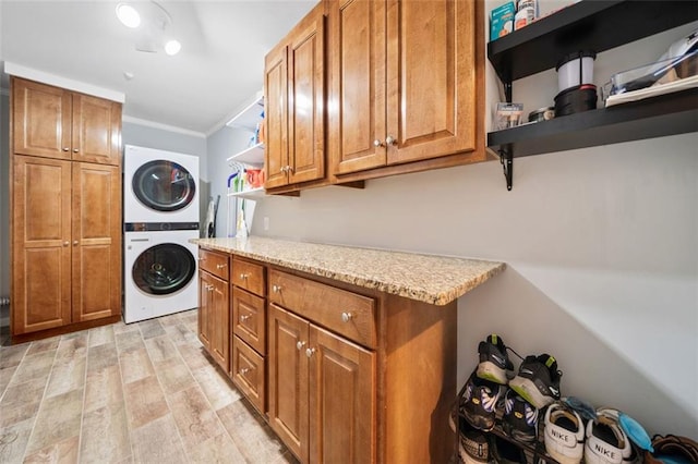 3415 Trickum Rd, Woodstock, GA 30188 - clothes washing area featuring estacked washer and dryer, cabinet space, crown molding, and light wood-style floors