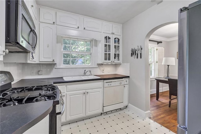 1908 E Roxboro Rd NE, Atlanta, GA 30324 - kitchen featuring appliances with stainless steel finishes, dark countertops, arched walkways, white cabinetry, and light floors