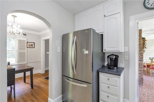 1908 E Roxboro Rd NE, Atlanta, GA 30324 - kitchen featuring freestanding refrigerator, arched walkways, white cabinets, dark countertops, and wood finished floors