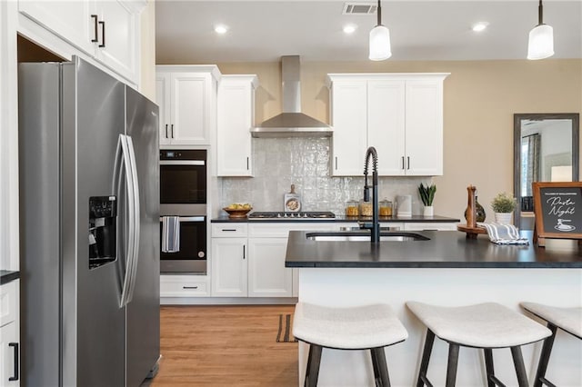 702 Smokey Quartz Way, Kennesaw, GA 30144 - kitchen featuring stainless steel appliances, wall chimney range hood, dark countertops, a sink, and a kitchen bar