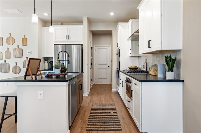 702 Smokey Quartz Way, Kennesaw, GA 30144 - kitchen with stainless steel appliances, dark countertops, a breakfast bar area, light wood-style flooring, and a center island with sink
