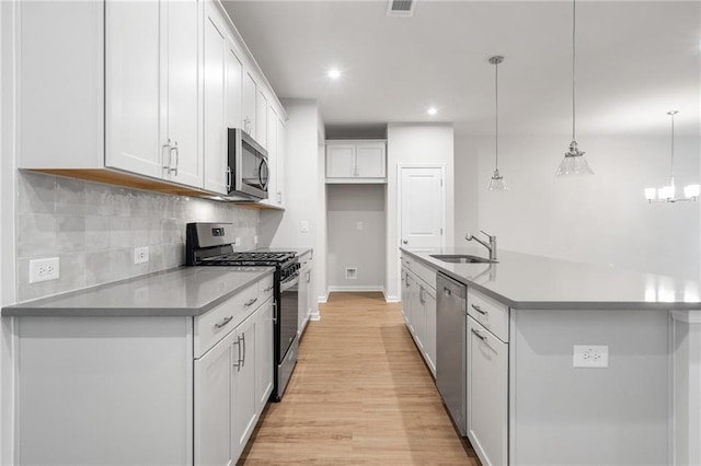 702 Smokey Quartz Way, Kennesaw, GA 30144 - kitchen featuring appliances with stainless steel finishes, a sink, light wood-type flooring, decorative backsplash, and white cabinets