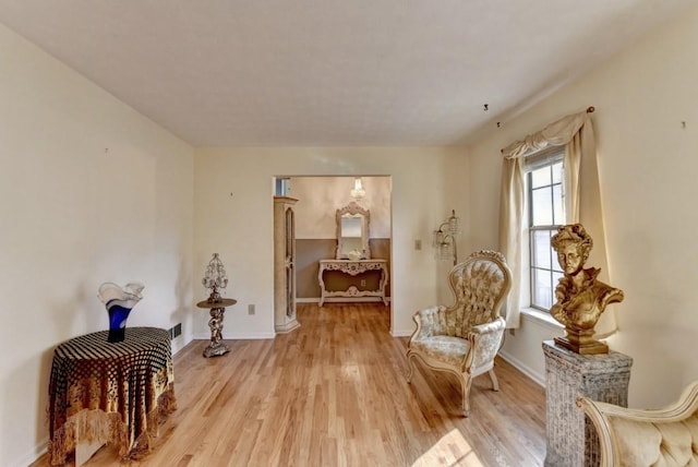 living area featuring light wood-type flooring, visible vents, and baseboards