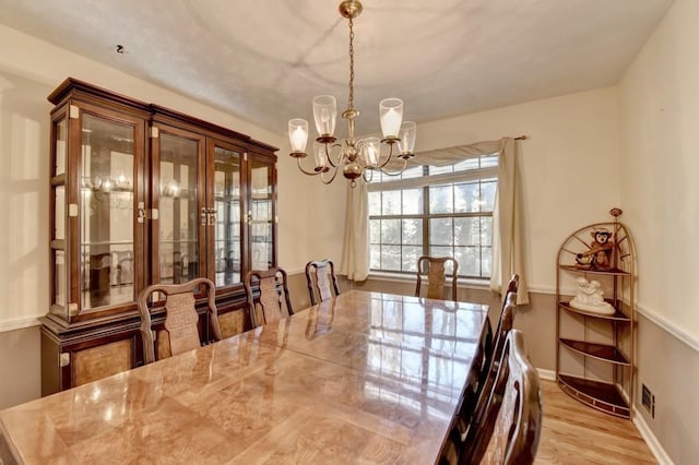 dining room featuring light wood-style flooring, a chandelier, and baseboards