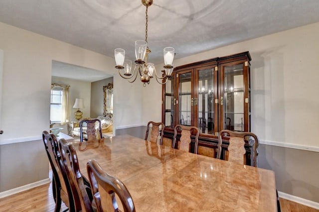 dining room with an inviting chandelier, baseboards, and wood finished floors