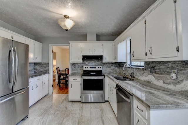 kitchen with white cabinets, appliances with stainless steel finishes, a sink, under cabinet range hood, and backsplash
