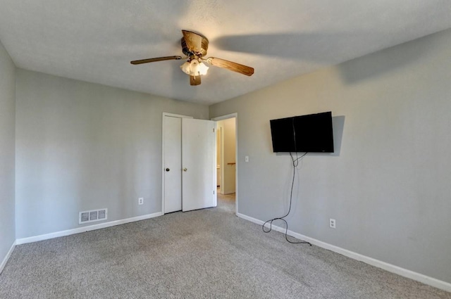unfurnished bedroom with carpet floors, a ceiling fan, visible vents, and baseboards