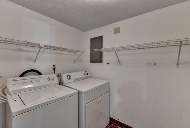 washroom with a textured ceiling, laundry area, baseboards, washer and dryer, and electric panel
