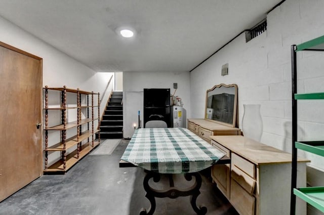 dining room with concrete flooring, water heater, stairs, and concrete block wall
