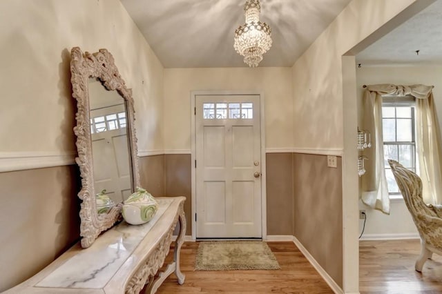 entryway with baseboards, an inviting chandelier, and wood finished floors