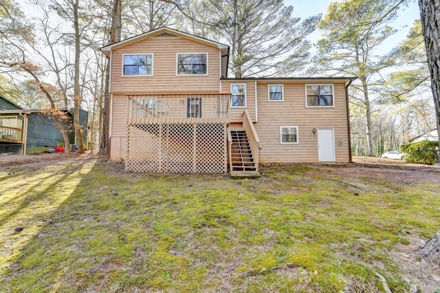 rear view of property with stairway, a deck, and a lawn