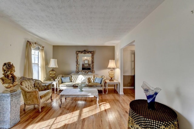 living area featuring a textured ceiling, wood finished floors, and baseboards