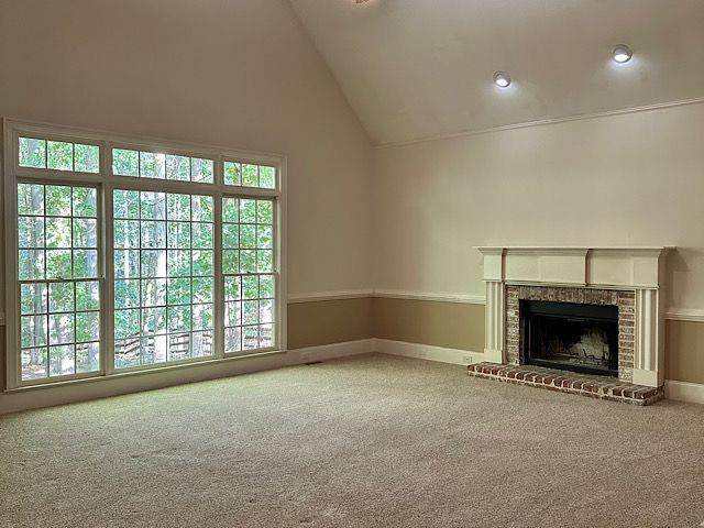 unfurnished living room with a fireplace, carpet, and high vaulted ceiling