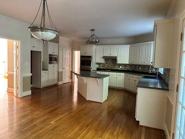 kitchen featuring dark hardwood / wood-style flooring, stainless steel appliances, sink, white cabinets, and a kitchen island