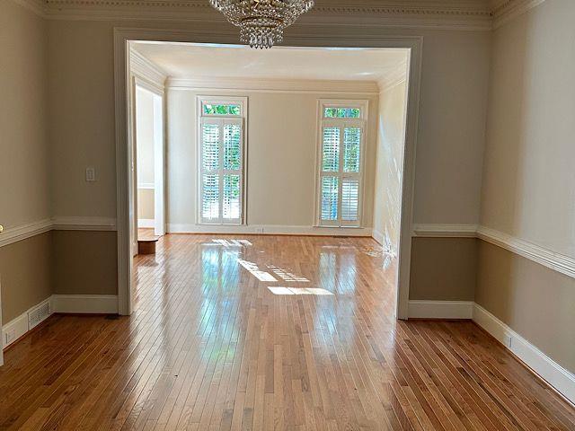 interior space with an inviting chandelier, wood-type flooring, and ornamental molding