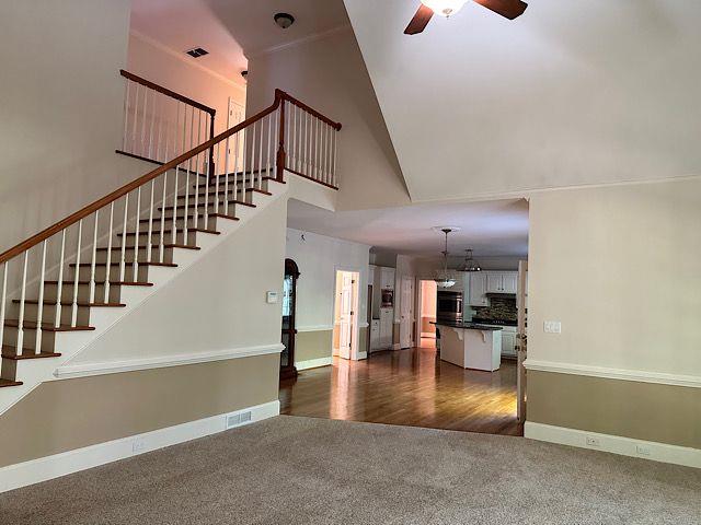 unfurnished living room featuring ceiling fan, high vaulted ceiling, and dark wood-type flooring