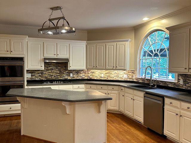 kitchen with white cabinets, a kitchen island, sink, and appliances with stainless steel finishes